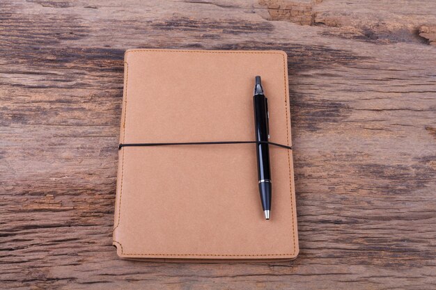 Blank note pad with pen on wood background