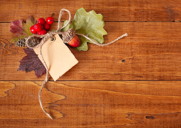 blank note with autumn leaves and acorns on wooden surface with copy space