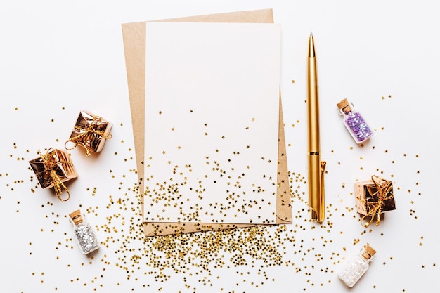 Blank note with envelope, gifts, pen and gold glitter stars on white background