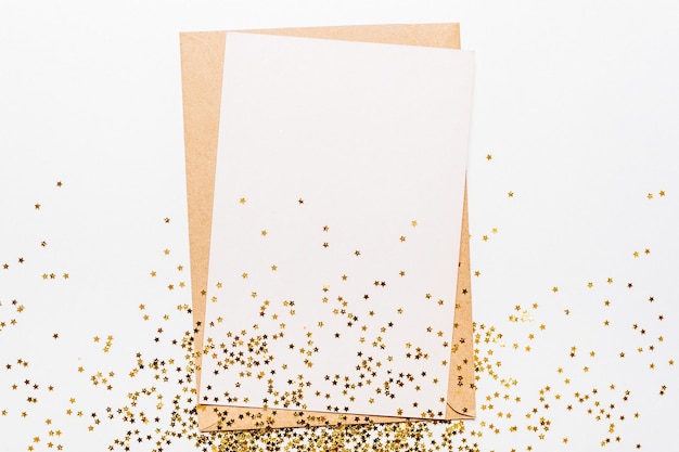 Blank note with envelope and gold glitter stars on white background