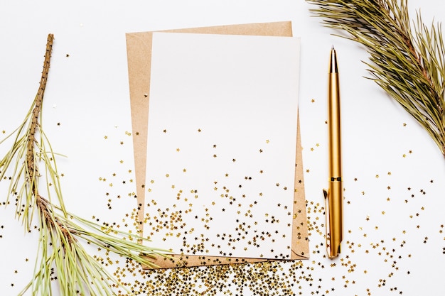 Blank note with envelope, spruce branch and gold pen on white background