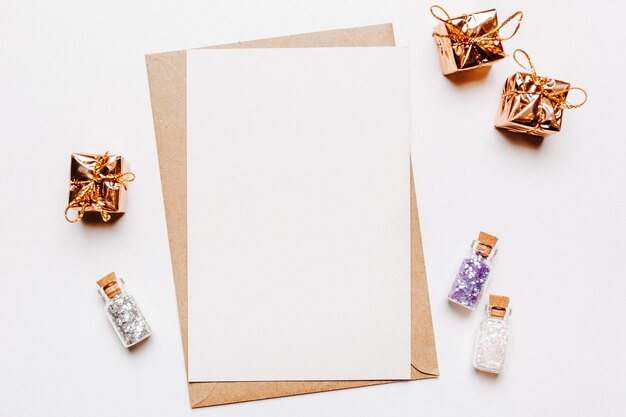 Blank note with gifts and glitter on white background