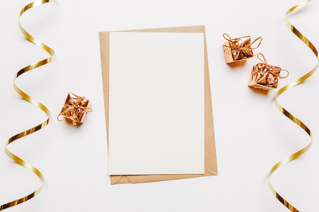 Blank note with gifts and gold ribbon on white background