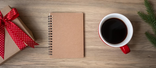 Blank notebook black coffee cup and Christmas gift on wood table Top view and copy space Xmas Happy New Year Goals Resolution To do list Strategy and Plan concept