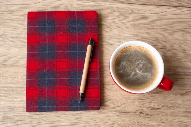 Blank notebook, coffee cup and pen on wood table. happy new\
year, goals, resolution, to do list, strategy and plan concept