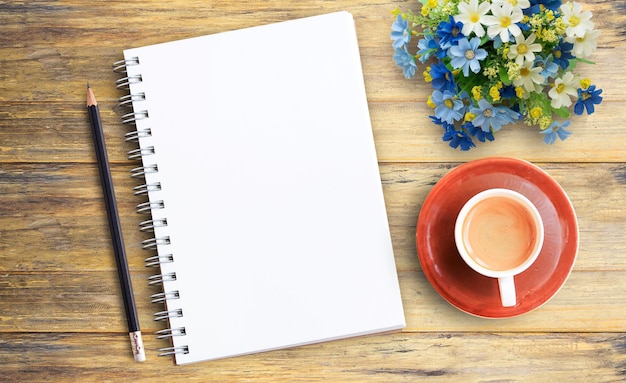 空白のノートと木製のテーブルの上のコーヒーのカップ