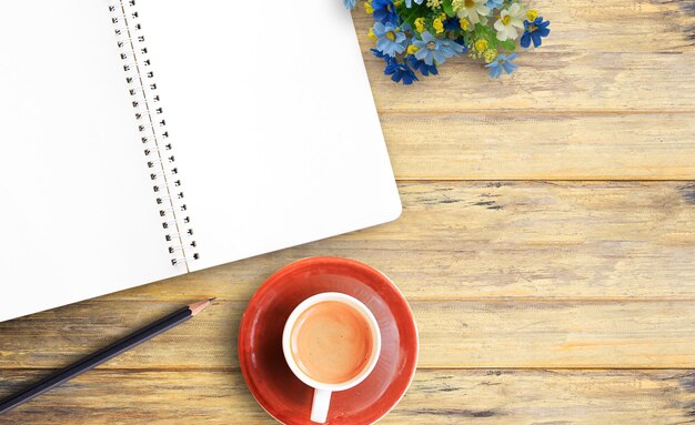 Blank notebook and cup of coffee on wooden table