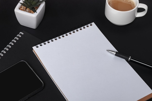 Blank notebook and different office supplies on dark background copy space