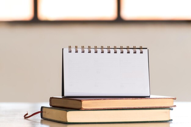 Photo blank notebook on stacked books and behind a bright window planning space for copy