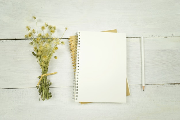 Blank notebook with dried flower and pencil on white background