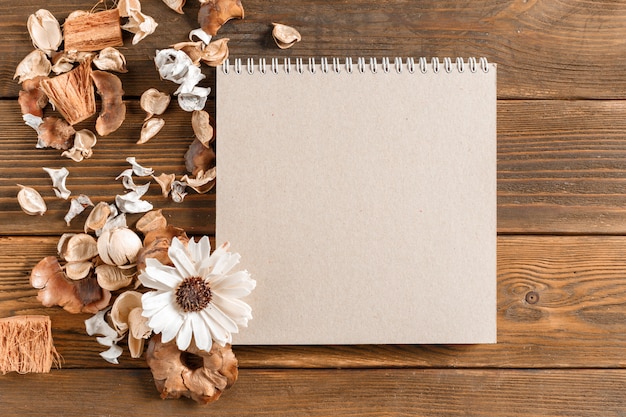 Blank notebook with flower on vintage wooden table