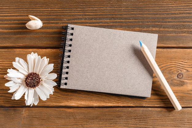 Blank notebook with flower on vintage wooden table