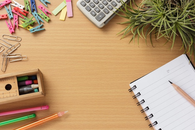 Blank notebook with office stationery on wooden desk.