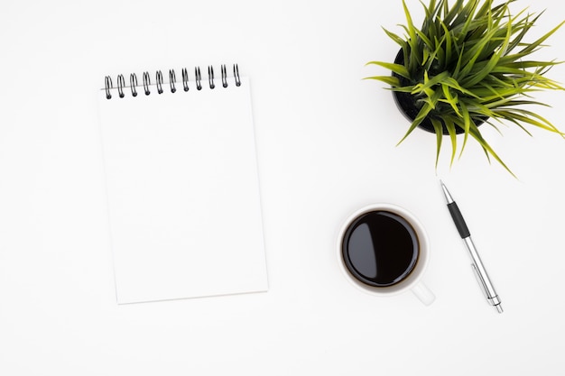 Photo blank notebook with pen are on top of white office desk table with cup of coffee.
