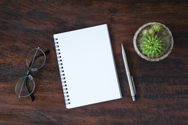 Blank notebook with pen is on top of white desk table. Top view, flat lay.