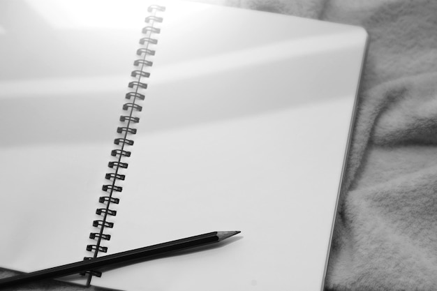 A blank notebook with a pen on it is on a marble table.