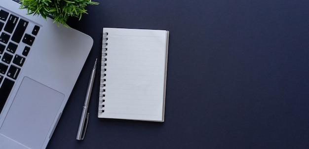 Photo blank notebook with pen and laptop on black table background