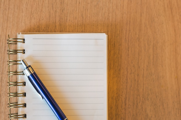 Blank notebook with pen on wooden desk