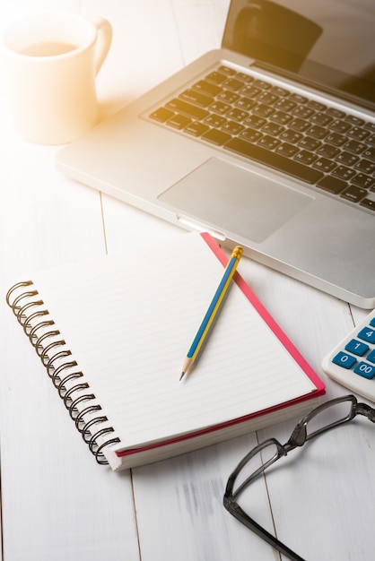 Blank notebook with pencil and laptop 