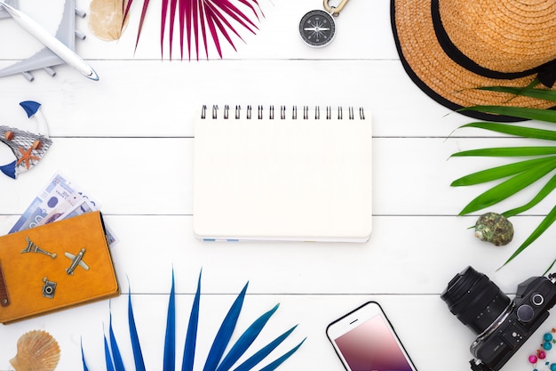 Blank notebook with travel accressories and palm leaves 