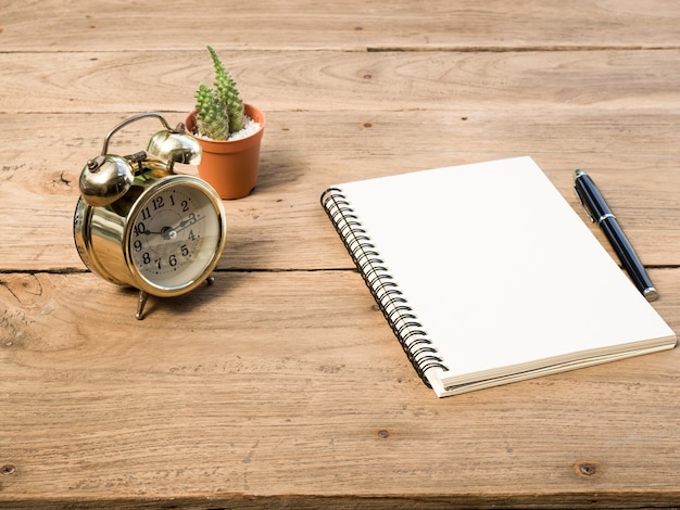 Blank notebook with vintage alarm clock and black pen 