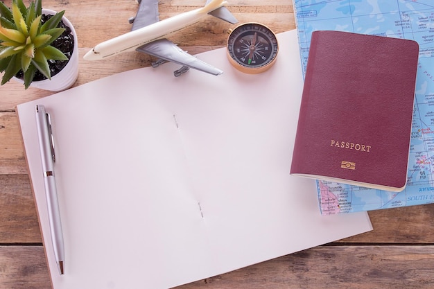 Photo blank notebookpassportcompassairplane and map on wooden table