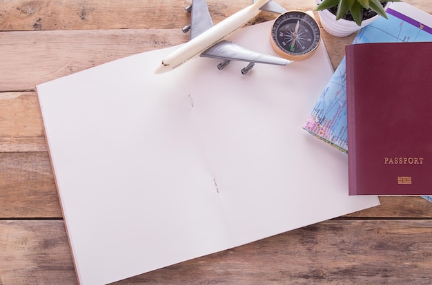 Photo blank notebookpassportcompassairplane and map on wooden table