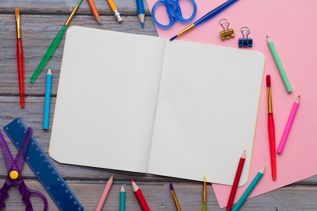 Blank notepad and childrens art supplies on a wooden background