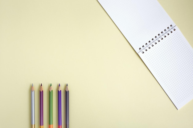 Blank notepad and colored pencils on a yellow background