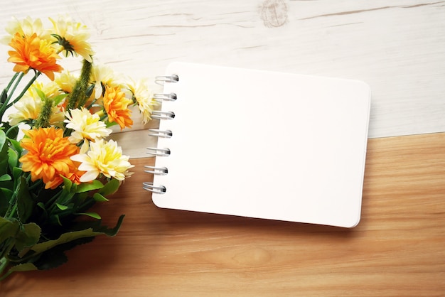 Foto blocco note e fiore in bianco su fondo di legno bicolore