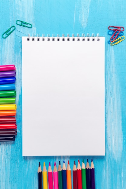 blank notepad page with pencils, markers, paper clips. Back to school concept.