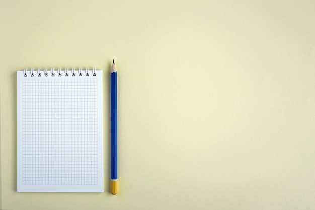 Blank notepad and pencil on a yellow background