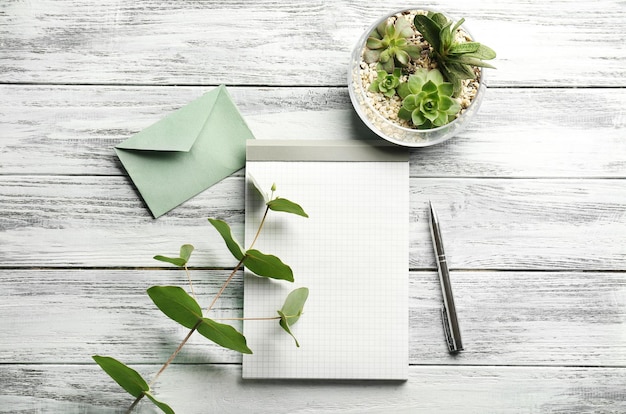 Blank notepad and succulents on wooden background