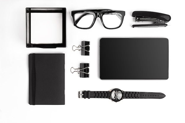 blank notepad with clips, pens and glasses flat lay. top view on set of black office supplies and spectacles on a white background