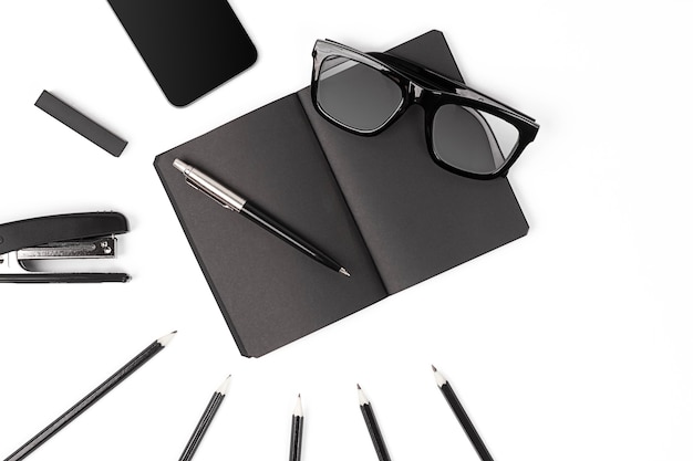 Blank notepad with clips, pens and glasses flat lay.