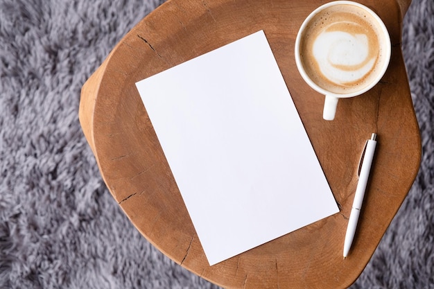 blank notepaper mockup on coffee table with cappuccino pen and grey rug