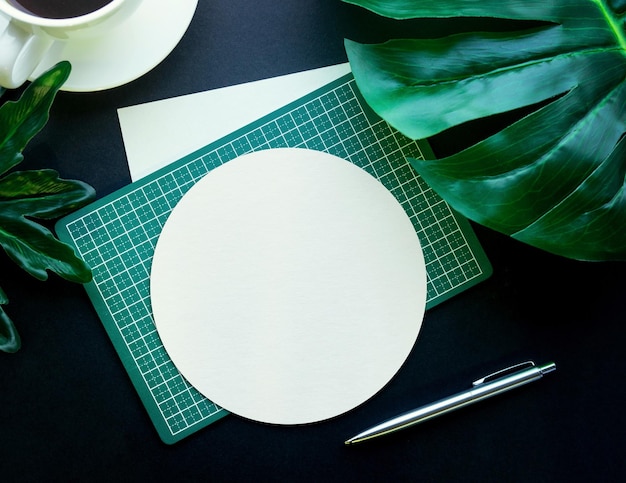 Blank notepaper with tropical leaves and accessories laying on black tableHome officeworkspace design backgroundflat laytop view