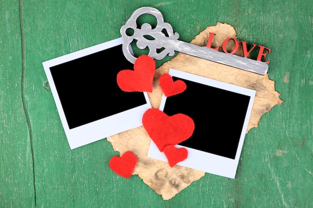 Photo blank old photos and decorative key hearts on color wooden background