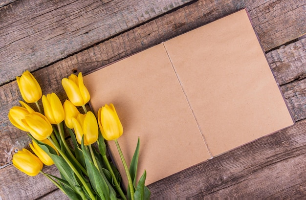 Blank open book with yellow tulips
