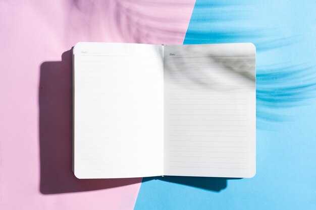 Photo blank open notebook on blue and pink surface