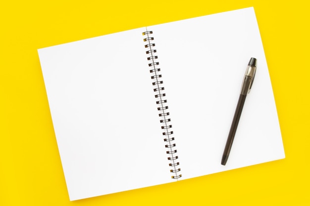 Blank open notepad on yellow background top view white notebook sheet with a spiral concept of the