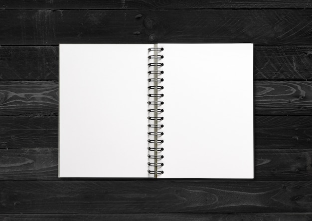 Blank open spiral notebook  isolated on black wood background