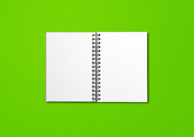 Blank open spiral notebook  isolated on green background