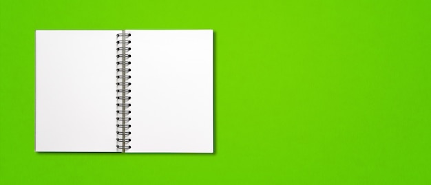 緑の水平バナーに分離された空白のオープンスパイラルノート
