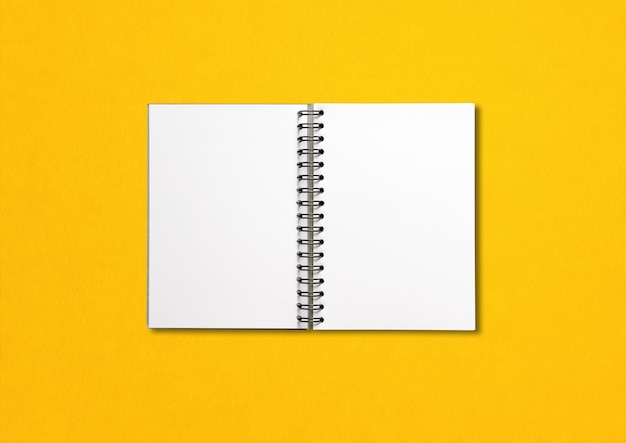 Blank open spiral notebook isolated on yellow background