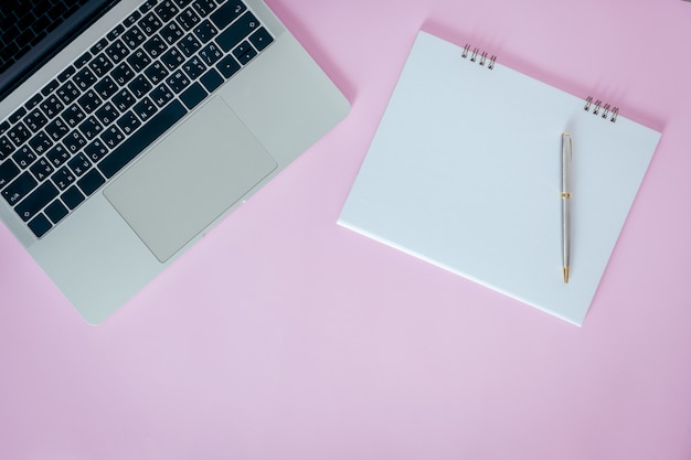 Photo blank opened notebook with laptop on pink background. flat lay, top view