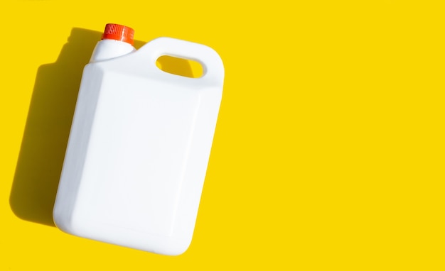 Blank packaging white plastic gallon on yellow background.