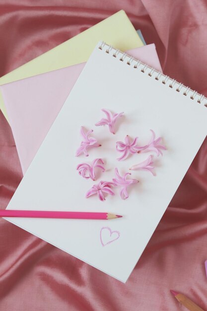 A blank page of a notebook is decorated with fresh hyacinth flowers, in the shape of a heart