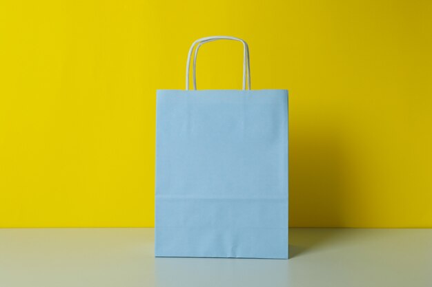 Blank paper bag against yellow