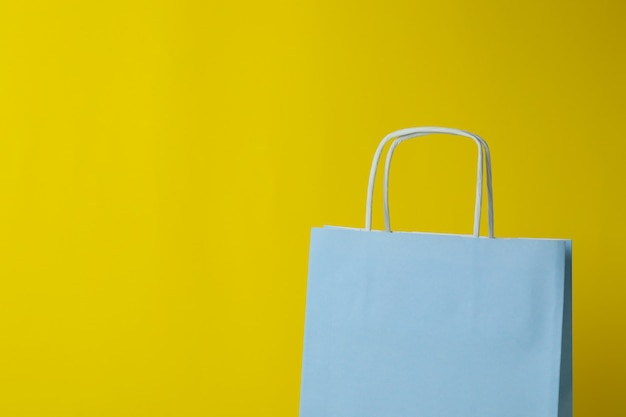 Blank paper bag against yellow